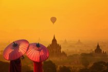Vista trasera de dos monjes con sombrillas que miran, Bagan, Mandalay, Myanmar - foto de stock