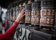 Die Hand einer Frau berührt eine Gebetsmühle, Nepal — Stockfoto