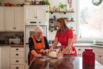 Seniorin lehrt ihre Tochter Brot backen — Stockfoto