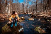 Girl sitting on a rock in the middle of a river, USA — Stock Photo