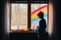 Junge malt einen Regenbogen auf ein Fenster, USA — Stockfoto