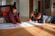 Três crianças trabalhando em um projeto de arte em casa — Fotografia de Stock