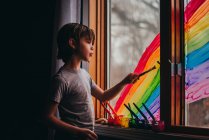 Ragazzo che dipinge un arcobaleno su una finestra, USA — Foto stock