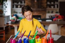 Дівчина сидить на кухні малює веселку — стокове фото