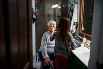 Menina colocando maquiagem em sua avó — Fotografia de Stock
