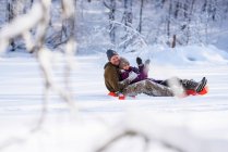 Uomo e donna slittino giù per una collina nella neve, Stati Uniti — Foto stock