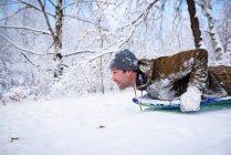 Man tubing down a hill in the snow, Estados Unidos - foto de stock