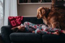 Fille couchée sur un canapé avec son chien — Photo de stock