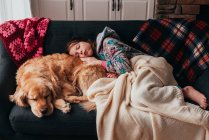 Mädchen schläft auf einem Sofa mit ihrem Hund — Stockfoto