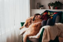 Дівчина спить на дивані зі своїм собакою — стокове фото