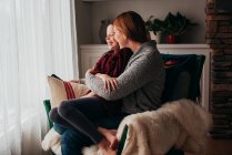 Mother and daughter cuddling in an armchair — Stock Photo