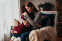 Girl sitting on her mother's lap cuddling — Stock Photo