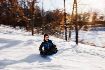 Junge schlittert im Schnee einen Hügel hinunter, USA — Stockfoto