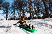 Хлопчик на санях униз по схилу снігу, США. — стокове фото