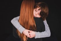 Vista trasera de una mujer abrazando a su hijo - foto de stock