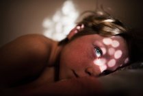 Boy lying in bed with sunlight on his face — Stock Photo