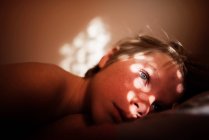 Мальчик лежит в постели с солнечным светом на лице — стоковое фото