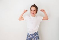 Mädchen steht an einer Wand und lässt ihre Muskeln spielen — Stockfoto