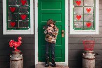 Мальчик, стоящий перед курятником, обнимающий курицу, США — стоковое фото