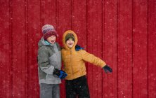 Двое счастливых детей возятся перед красным домом, США — стоковое фото