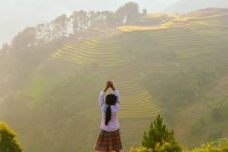 Woman standing in front of terraced rice fields at sunset, Mu Cang Chai, Vietnam — Stock Photo