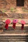 Tres monjes novicios subiendo escaleras a un antiguo templo, Bagan, Mandalay, Myanmar - foto de stock