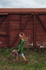 Donna che cammina all'aperto portando un mazzo di fiori lilla — Foto stock