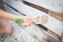 Pintar una paleta reciclada con un pincel blanco - foto de stock