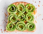Toast with avocado roses, chilli flakes and edible flowers — Stock Photo