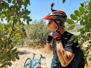 Ciclista que se pone un casco de ciclismo con cámara portátil, Malta - foto de stock