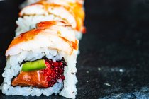 Primer plano de maki roll con tobiko, aguacate, salmón, gambas y queso crema - foto de stock