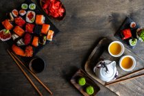 Вид сверху на суши из нигири и рулонов маки с васаби, маринованным имбирем и зеленым чаем — стоковое фото