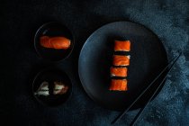 Набор суши с рулонами филаделии подается на каменном столе с палочками для еды — стоковое фото