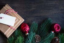 Pila di regali di Natale accanto a pigne, rami di abete e ornamenti di Natale su una tavola di legno — Foto stock