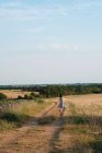Vue arrière d'une femme courant le long d'une route de campagne, France — Photo de stock