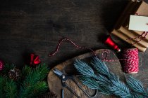 Стек різдвяних подарунків поруч з пінцетами, ялинковими гілками та різдвяними прикрасами на дерев'яному столі — стокове фото