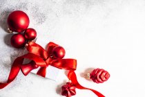 Geschenkverpackung mit roter Schleife und Christbaumkugeln — Stockfoto