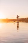 Jovem mulher levante-se paddleboarding ao pôr do sol, Lago Wallersee, Flachgau, Salzburgo, Áustria — Fotografia de Stock