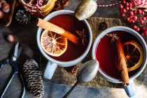 Cups of mulled wine with cinnamon and orange on a chopping board — Stock Photo
