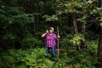 Donna anziana felice escursioni nella foresta raccogliendo un fiore, Stati Uniti d'America — Foto stock