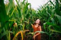 Chica sonriente jugando en un campo de maíz, EE.UU. - foto de stock