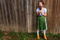 Chica parada junto a una valla comiendo una pierna de pavo asada, EE.UU. - foto de stock