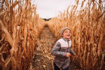 Rapaz feliz correndo através de um campo de milho no outono, EUA — Fotografia de Stock