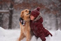 Girl sitting in the snow cuddling her golden retriever dog, Wisconsin, USA — Stock Photo
