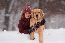 Fille assise dans la neige câlinant son chien golden retriever, Wisconsin, USA — Photo de stock