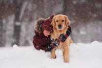 Girl sitting in the snow cuddling her golden retriever dog, Wisconsin, USA — Stock Photo