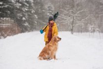 Junge mit Schaufel steht mit seinem Hund im Schnee auf einer langen schneebedeckten Einfahrt, Wisconsin, USA — Stockfoto