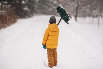 Junge mit Schaufel steht im Schnee auf einer langen schneebedeckten Einfahrt, Wisconsin, USA — Stockfoto