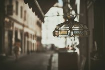 Glass lamp hanging in vintage market stall with woman in distance, Spain — Stock Photo