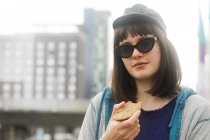 Porträt einer lächelnden Frau, die draußen steht und ein Stück Brot isst, Deutschland — Stockfoto